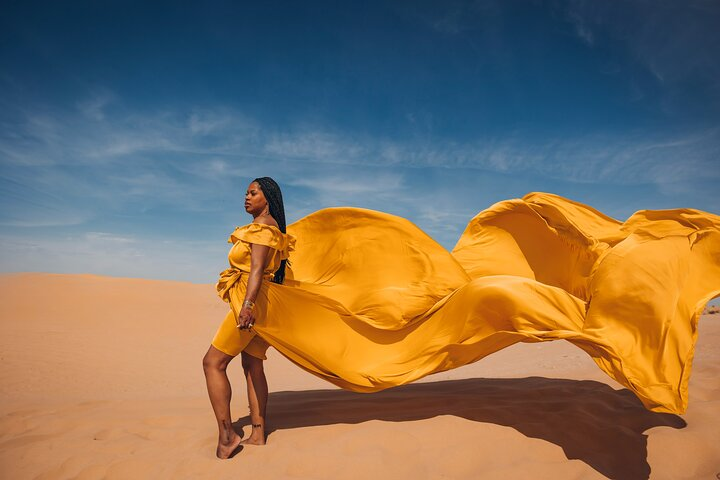 Experience the magic of the Dubai desert as flowing dresses dance in the wind creating unforgettable moments amidst stunning sandy landscapes and a brilliant blue sky. Capture every detail!